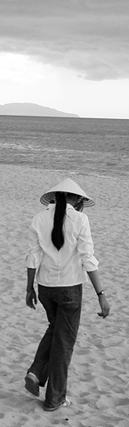young woman with traditional straw hat walking on beach